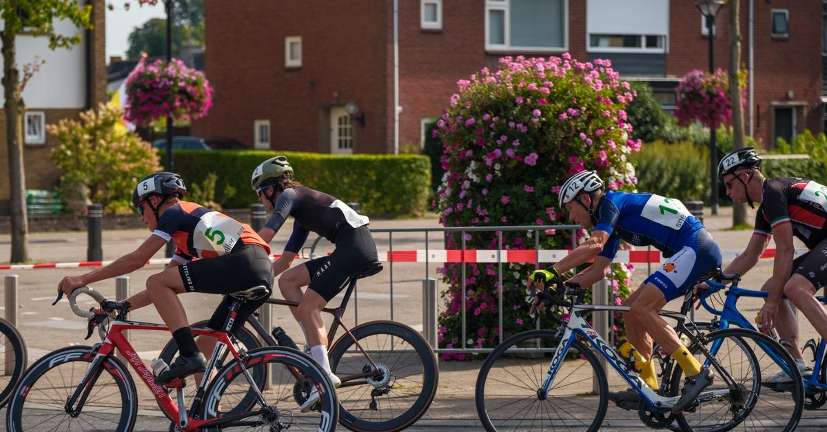 Competitive cyclists race through a sunny urban area during a thrilling road cycling event.